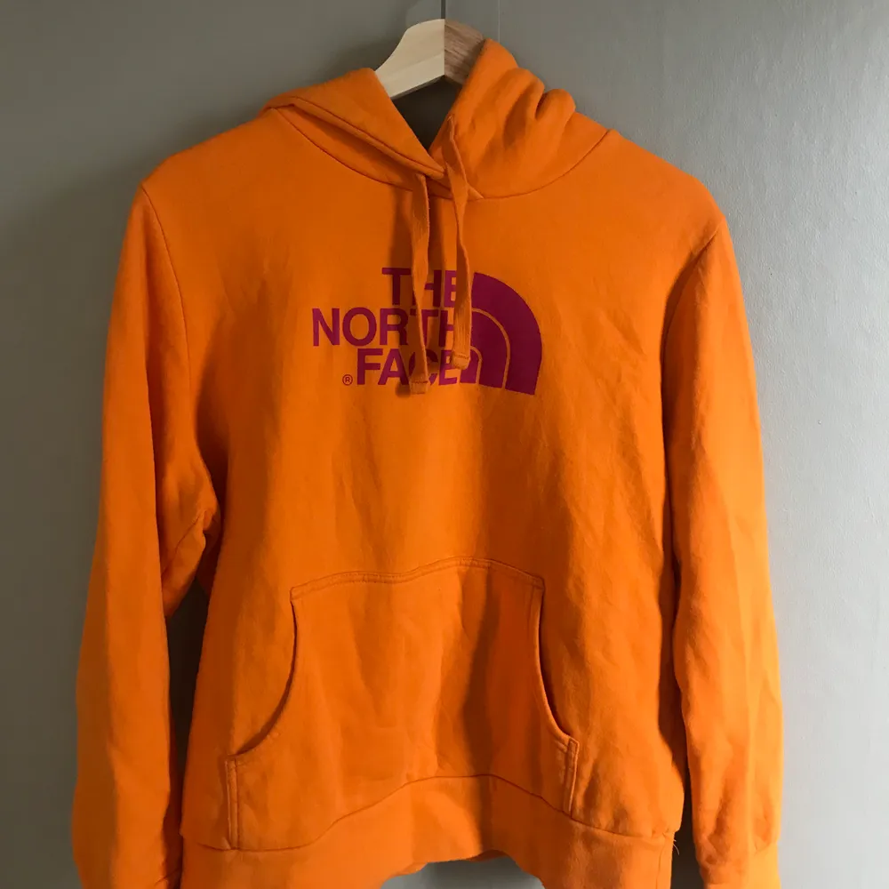Orange hoodie med rosa tryck från The North Face. Storlek L men massage S-L. Mycket bra skick. Frakt ingår ej. SÄNKT PRIS 150kr‼️. Hoodies.