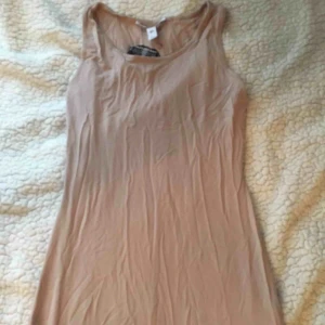  - En lång klänning i färgen ”Nude”, som aldrig är använd. Den behöver strykas en aning. Klänningen är i storlek XS, passar även mig som egentligen har SMALL, så borde passa medium också då den är stretchig!