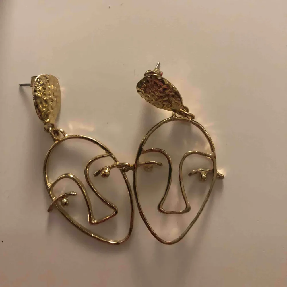 Guldiga örhängen med ansikten från Glitter. Knappt använda. Nypris: 30 kr. Accessoarer.