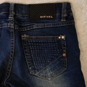 Diesel jeans blå 27/32 - Low waist, aningens lose fit/Slim fit.  Modell Zatiny.  W27 L32. 100% bomull.  Säljes pga för små.  Lite små slitningar men det hör till designen.  Använt sparsamt.  Köparen står för frakten, fraktförslag mottages gärna.  Samfraktar.