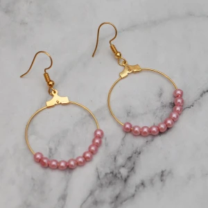  - Fina guldfärgade örhängen med rosa pärlor. Nickelfria.  Obs! Örhängena är inte orangea som på bilden, Photoshop ändrar färgerna för mig 🙃 Fri frakt vid köp över 100:-.