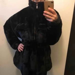  - Svart jättefin faux fur kappa med knytning som markerar midjan samt dragkedja hela vägen upp i kragen. Så mjuk, mysig och varm! Helt oanvänd, prislapp kvar. Säljer pga har för många jackor.  Kan mötas upp i Sthlm, annars tillkommer frakt 