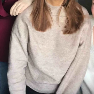  - En beige tröja i hög krage som är mjuk. 