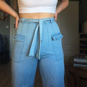 Ett par wide leg jeans i tunt tyg från asos med sidofickor och bälte. De är i storlek 38.