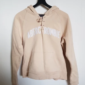 Beige Hoodie - Beige hoodie från abercrombie, frakt ingår i priset. Betalar via swish. Den är lite liten i storleken och är ganska använd och är köpt för väldigt länge sen, men den är inte nopprig. Luvan är ganska stor.