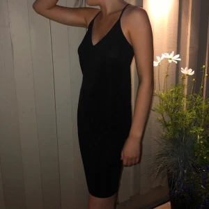 Svart klänning med tunna band  - En tvärsnygg klänning i polyester!! Lika fin till stranden som fest. Banden är ganska långa så det jag gjort är att knyta dem uppe vid axlarna. Strl står ej, men min syster på bilden är S och den passar, men passar också M & L! Köpare står för frakt.
