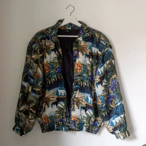 Retro bomber med fint mönster - Fin tunn vintage jacka med härligt mönster i bombermodell. Med muddar och två praktiska fickor. I fint skick! Utsidan 100% silke och foder 100% polyester. Obs! Saknar dragkedja, jag har använt den öppen, det går att sy på en lätt om en vill.