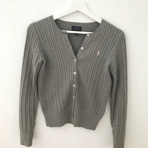 Ralph Lauren- kofta - Grå kofta från Ralph Lauren. Använd ett fåtal gånger och är i utmärkt skick. Säljer eftersom att den blivit för liten och inte längre används. Köpt i strl L på barnavdelningen, motsvarande XS i vuxen strl.   Storlek: XS    Pris: 80kr + frakt