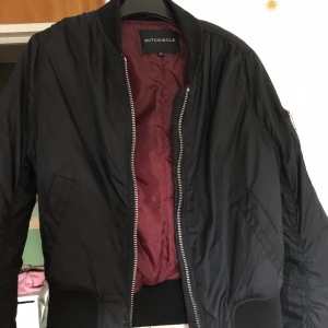 Bomberjacka - Svart bomberjacka med vinröd insida, säljer pga för liten. Använd 2-3 gånger, storlek 32.