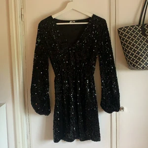 Svart Paljettklänning - En jättefin svart paljettklänning ifrån Nelly, i storlek 34. Använda 1-3 gånger. Har en liten urringning och lite ballongarm. Köpt för 500kr.