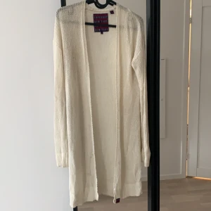 Cardigan  - Lång krämvit cardigan i luftigt material 