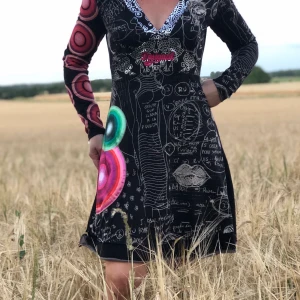 Desigual klänning - Vacker v-ringad klänning med mönster och detaljer frampå. Knappt använd och modellen på bilden är ca 160 cm lång.