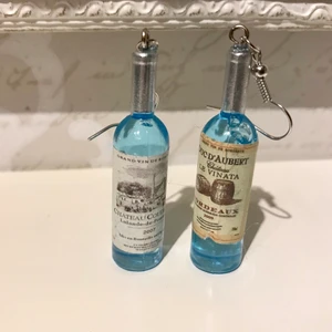 🍸🥳NYA INPLASTADE AKRYL ÖRHÄNGEN LIKÖR FÖASKOR💎🍸 - 🥳😀PARTY BLÅA AKRYL FLASKOR ETT PAR NYA VINFLASKOR MED GLITTRIG GYLLENDE TYG ETUIET, enligt bilder* Bjuder på portot. 🥳😀🍸🍸🍸🍸