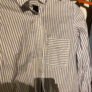 En randig vit mörk blå skjorta den är i ny skick använd bara ett par gånger köpt från italien buda gärna pris och så klart om du köper flera plagg så blir det annat pris❣️❣️