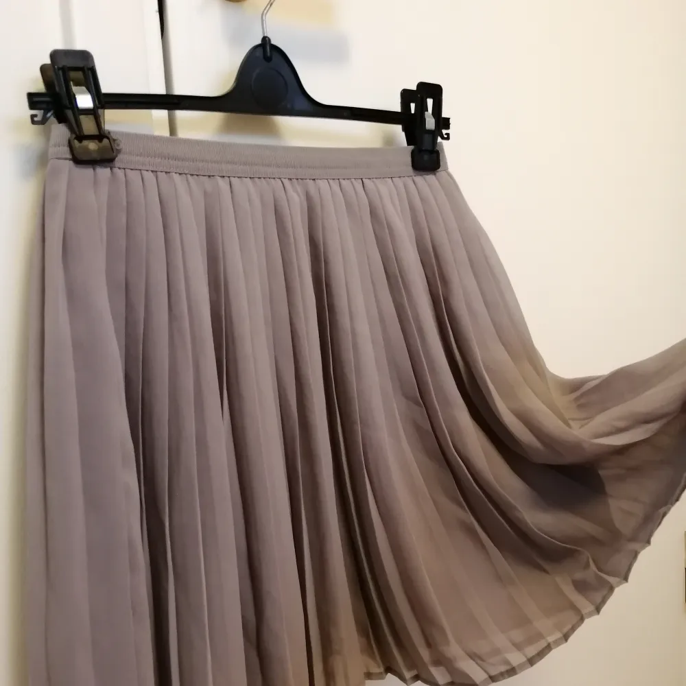 Gullig, kort kjol i en ljusgrå färg. Från Uniqlo, stl xs. Elastisk runt midjan och två lager. 100% polyester. . Kjolar.