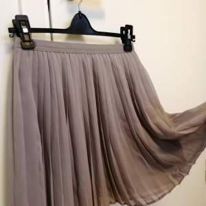 Gullig, kort kjol i en ljusgrå färg. Från Uniqlo, stl xs. Elastisk runt midjan och två lager. 100% polyester. 