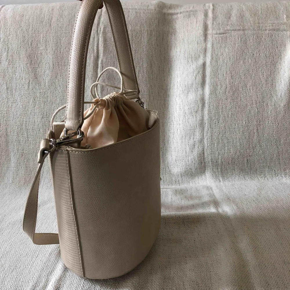 Benvit/ljus beige liten men rymlig bucketbag.  Hämtas upp i Stockholm eller köpare står för frakt.. Väskor.