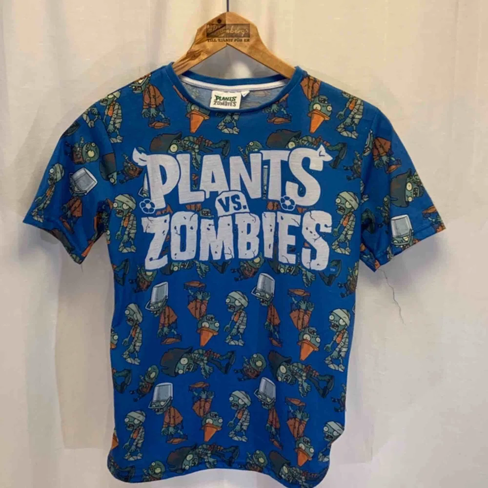 Plants vs Zombies t-shirt. Storlek S i mycket gott skick. Kan hämtas i Uppsala eller skickas mot fraktkostnad.. T-shirts.