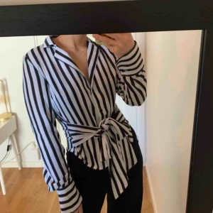  - Svart-vit-randig blus, med knytning i midjan ursprungligen från NA-KD. Använd endast en gång, superfint skick. 