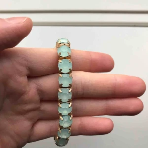  - Armband för 10kr (+frakt på 9kr)  Guldfärgad med ljusblåa stenar 