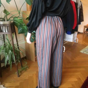  - vida högmidjade byxor i sidenliknande material. resår i midjan och sidfickor