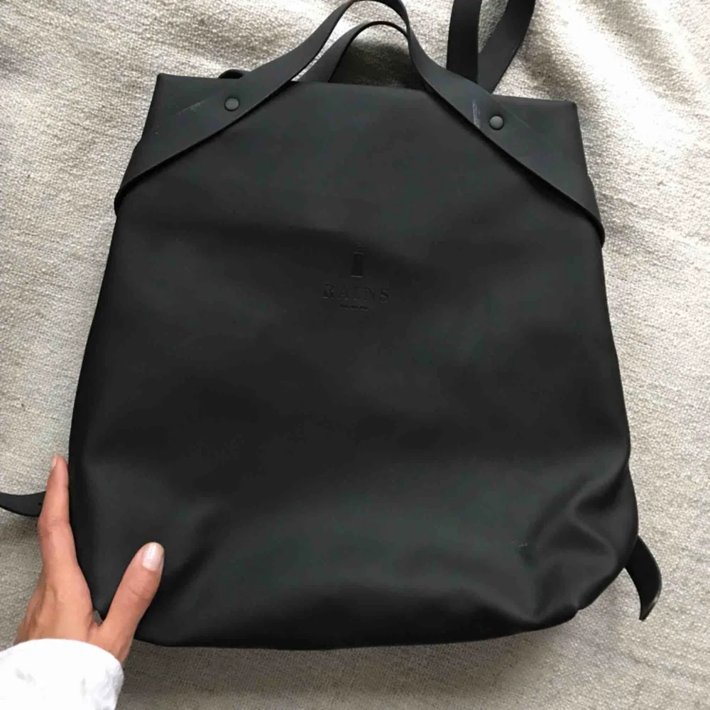 Gorgeous Rains backpack! Matte black, rubber feel. I only wore a couple times and then had to get a bigger bag that could fit all my yoga stuff :) There is a small rip inside lining of the back, but doesn’t affect the functionality. . Väskor.