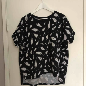  - Svart T-shirt med vita fjädrar på