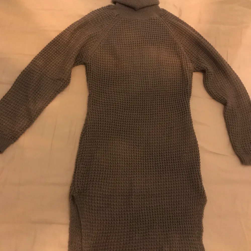 En lång mörkgrå stickad tröja med en liten slits i strl M. . Stickat.