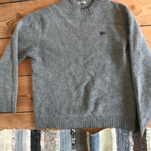 Stickad tröja med UCLA-logga. - Stickad varm tröja från UCLA, köpt second hand. Inte så nopprig som den ser ut på golvbilden tycker jag. Står ingen storlek men skulle säga att den sitter som en dam M eller unisex S. Hör av dig om du undrar något mer! Frakt står köparen för.