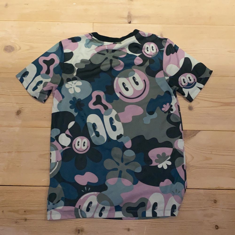 Sportig och cool mönstrad adidas t-shirt. 💚💙🖤💜🤍 Med stort adidastryck i vitt, mönstrad med blommor smileys och typ kamouflage, svart krage, och passar bra till träning, men kan även användas till vardags. 100% polyester. Mycket bra skick då den endast är använt fåtal gånger. XS men sitter lite oversized och snyggt på mig som är en XS/S. Funkar somsagt bra till träning och lek. DM vid intresse/fler frågor/ fler bilder.❣️(Det kan du göra här under för det står ”kontakta”) Avhämtning på Södermalm eller frakt till självkostnadspris.:). T-shirts.