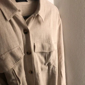 Beige cargoskjorta ASOS  - Köpt på ASOS, märket bershka. Knappt använd, mycket bra skick. Knytningar i midjan och knappar längst skjortan