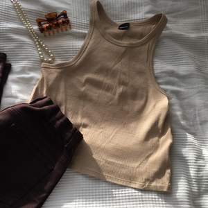 Ett High neck ribbat linne från Gina tricot. Storlek L, beige, ALDRIG ANVÄNT !! Nypris 150kr mitt pris 100kr❤️ säljer eftersom att det är för litet...