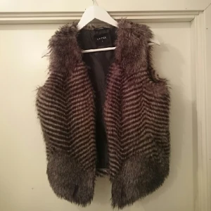 - Väst i naturtroget fuskskinn, bara använd ett fåtal gånger. Fin att ha till en tröja eller utanpå jackan.