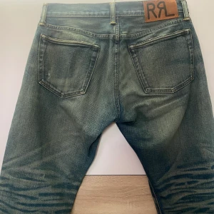 RRL Slim Fit Selvedge Jeans - Bara använd en gång för att se passform. Nytt skick. Ralph Laurens egna beskrivning: Slim-fitting jeans made from Ridgway Twill, Double RL's exclusive left-hand-twill denim. 13.7 oz. selvedge fabric is shuttle-woven in Japan. Turquoise cast inspired by 1950's American denim. Distressed by hand.