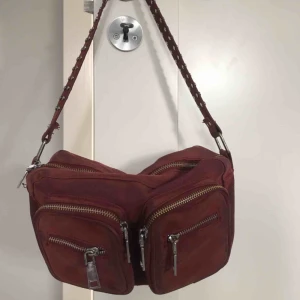 Noella väska - Säljer nu min noella väska. Mellanstorlek. Vinröd. Inga större skador utan endast lite små avskavningar på tyget ( se bild 2 ) du står för frakt. Köpt för 649 på noellas hemsida. Tillkommer även ett långt band🧚🏼‍♀️🧚🏼‍♀️🧚🏼‍♀️ pris kan diskuteras!!!