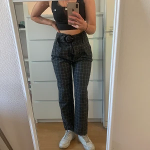 Rutiga lösa byxor från NAKD - Jättesnygga och sköna lösa rutiga byxor från NAKD!  Använda några gånger men i gott skick. Färgen på dem är en grå-svart nyans. 