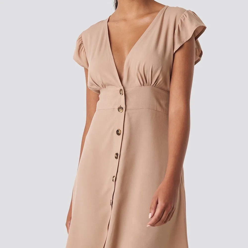Säljer denna beiga klänning från na-kd, storlek 34! Oanvänd med lapp kvar, säljes för 200kr inkl frakt!. Klänningar.