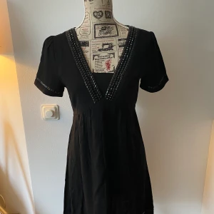 Vacker svart klänning med glitter - Vacker svart klänning med glittriga detaljer. Elegant och tidlös.