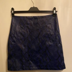 Oanvänd kjol från NAKD  - Mörkblå skinn kjol i ormskinns mönster. 