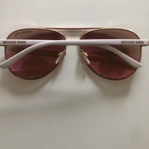 Michael Kors solglasögon  - Pilot solglasögon från Michael Kors. Vita plastbågar och glaset är i guld/rosé 