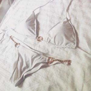  - Vit bikini med guldiga detaljer. Storlek S/M. Bra skick, har dock en liten fläck men syns knappt, men därav det billigare priset. Frakt betalas av köpare.