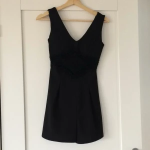  - Svart byxdress, med fint mönster framme på magen. 