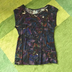  - Fin topp i återvunnet material. Snyggt mönster med blad/fjädrar i blå, lila och mörkröda detaljer.