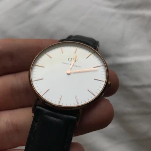  - Daniel Wellington med svart läderband.  Ur i roséguld.  Lädret kan behöver behandling samt någon mindre repa i glaset, därav det billiga priset.  