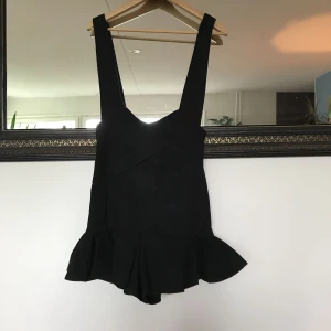  - Kort jeansklänning med hängslen. Figurnära med volangdetaljer. Oanvänd. Om den postas tillkommer frakt 