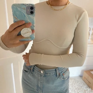 Beige topp - Superfin beige tight topp med en snygg detalj vid bröstet! Den är i väldigt bra skick, då jag inte använt den alls mycket. Köparen står för frakten💜