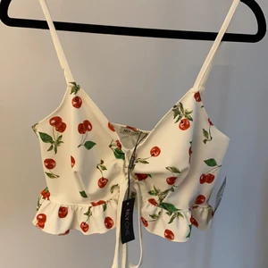 Lace upp cherry crop top - Croptop med knytning och cherry print från NLY One. Storlek M men går att justera mindre/större i och med knytningen. Oanvänd, nypris 300 kr.