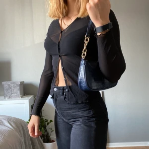 Genomskinlig tröja med knäppning - Svart genomskinlig tröja med knäppning centrerat fram. Fungerar lika bra som tunn kofta som bara en tröja. Lappen säger L men jag skulle säga S (jag har vanligtvis S) 50kr+frakt