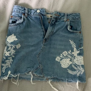 Jeanskjol med broderier - Jeanskjol i fint skick med vita broderier från Topshop. Nypris 500kr. Storlek 34. Köparen står för frakt.