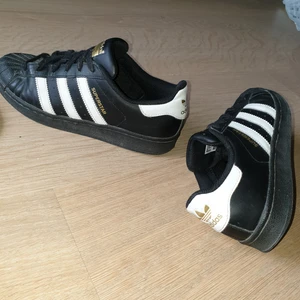 adidas superstar black - svarta adidas superstars med vita och guldiga detaljer, inte använda så mycket så de är i väldigt fint skick. strl 39